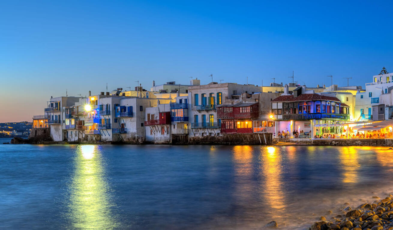 Small houses and restaurants on the sea at sunset.