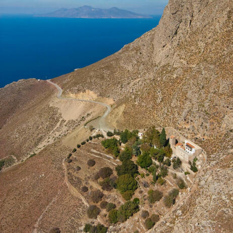 View from above of the mountainous volume of the island and of the port of Agios Antonios