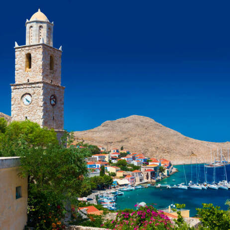 Church with bell tower overlooking the port of the island with the picturesque houses in the background