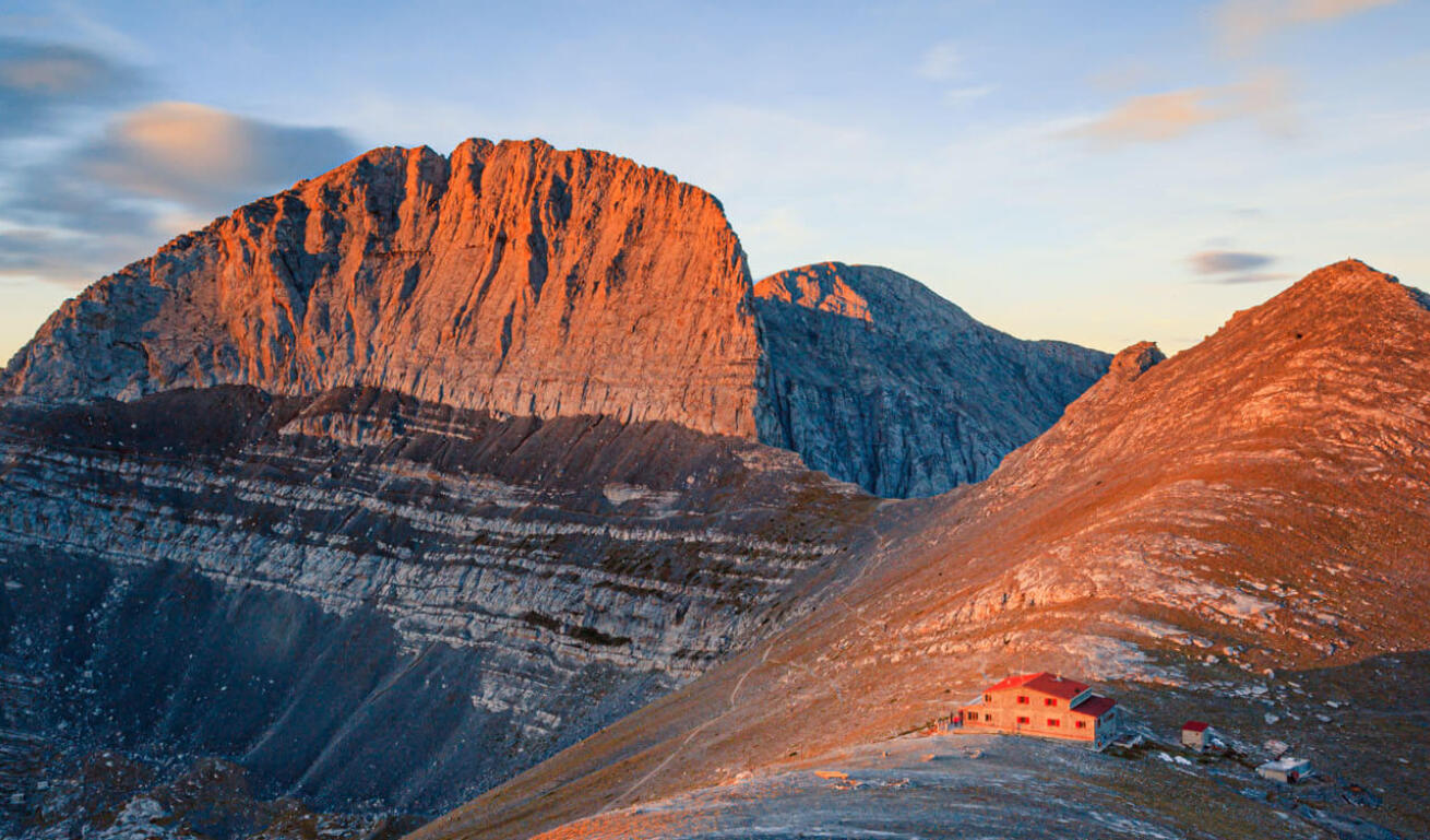 Rocky mountain top with a small shelter in the sunset.