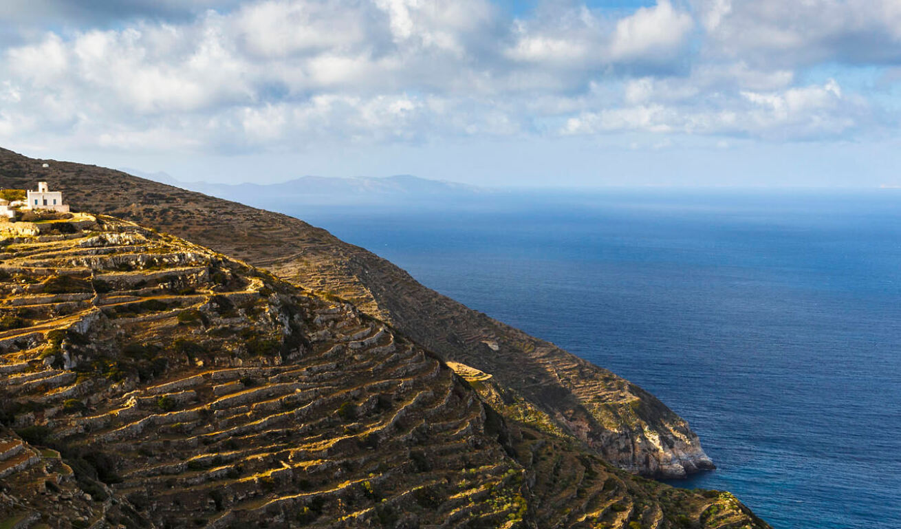 Μικρή άσπρη εκκλησία σε πλαγιά που καταλήγει στη θάλασσα.