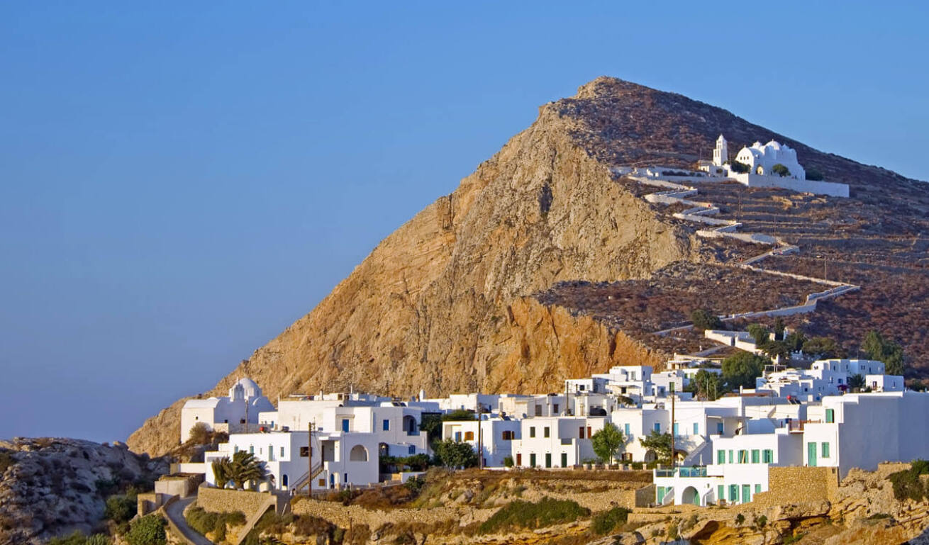 A small picturesque settlement with white houses and a church perched on a rocky hill, to which a white path leads. 