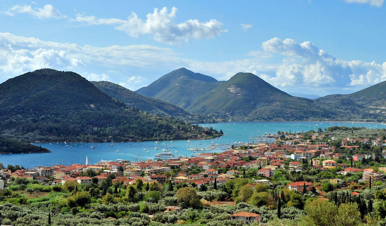 Άποψη του νησιού με τα γραφικά σπίτια, τα πράσινα δέντρα και τη θάλασσα γεμάτη με ιστιοφόρα