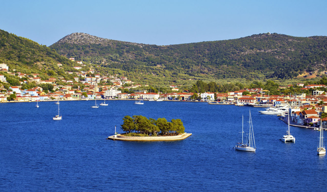 Tiny islet near the port of Ithaki with pine trees and surrounded by sailing boats