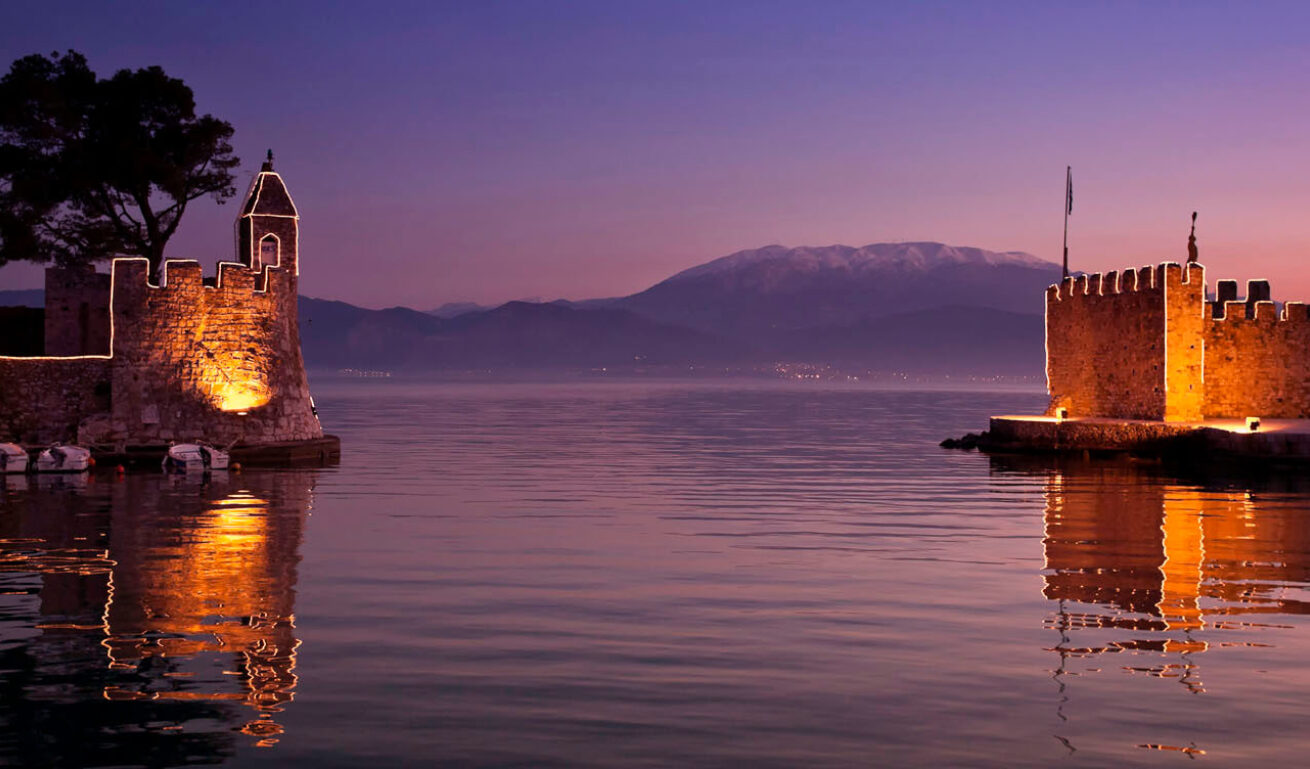 Θέα του λιμανιού το σούρουπο, με φωτισμένα τα τείχη της πόλης
