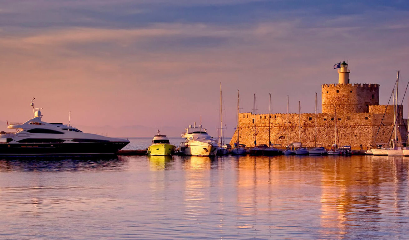 Άποψη του λιμανιιού δειλινό, με τα σκάφη και στα βάθος ο φάρος και το φρούριο του Αγίου Νικολάου