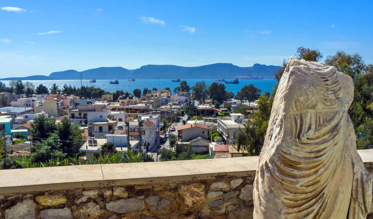Ancient statue without a head, with a view to the town of Elefsina and the port in the background