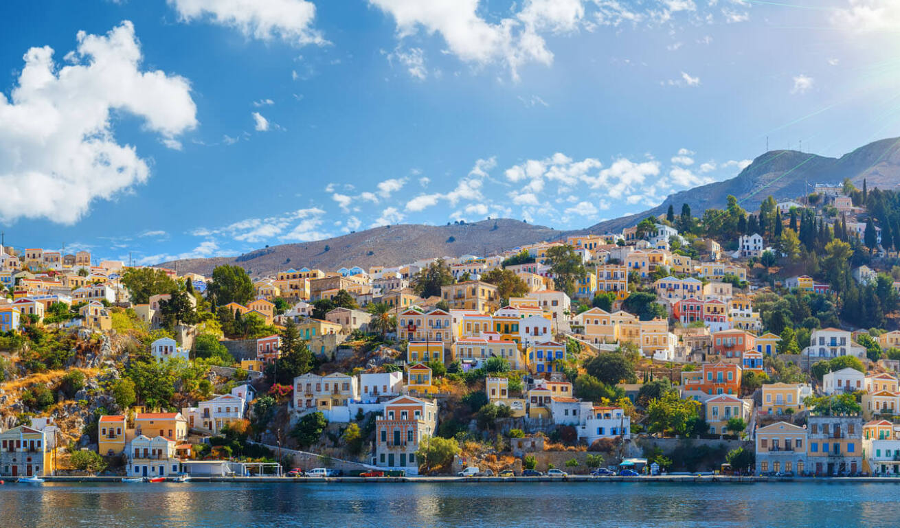 Traditional seaside village with colorful houses and trees under the sun.
