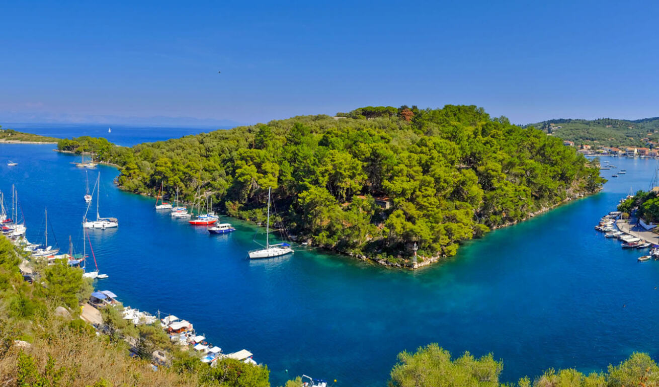 View of the island with a lot of sailing boats and fishing boats anchored and in the center a tiny green islet