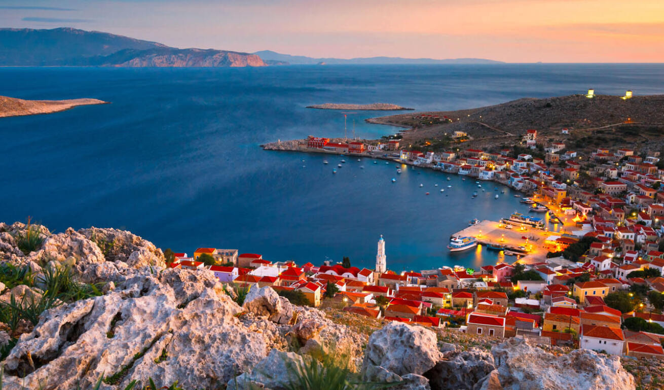 View of the island from above with the red rooftops of the picturesque houses and the illuminated port in the background 