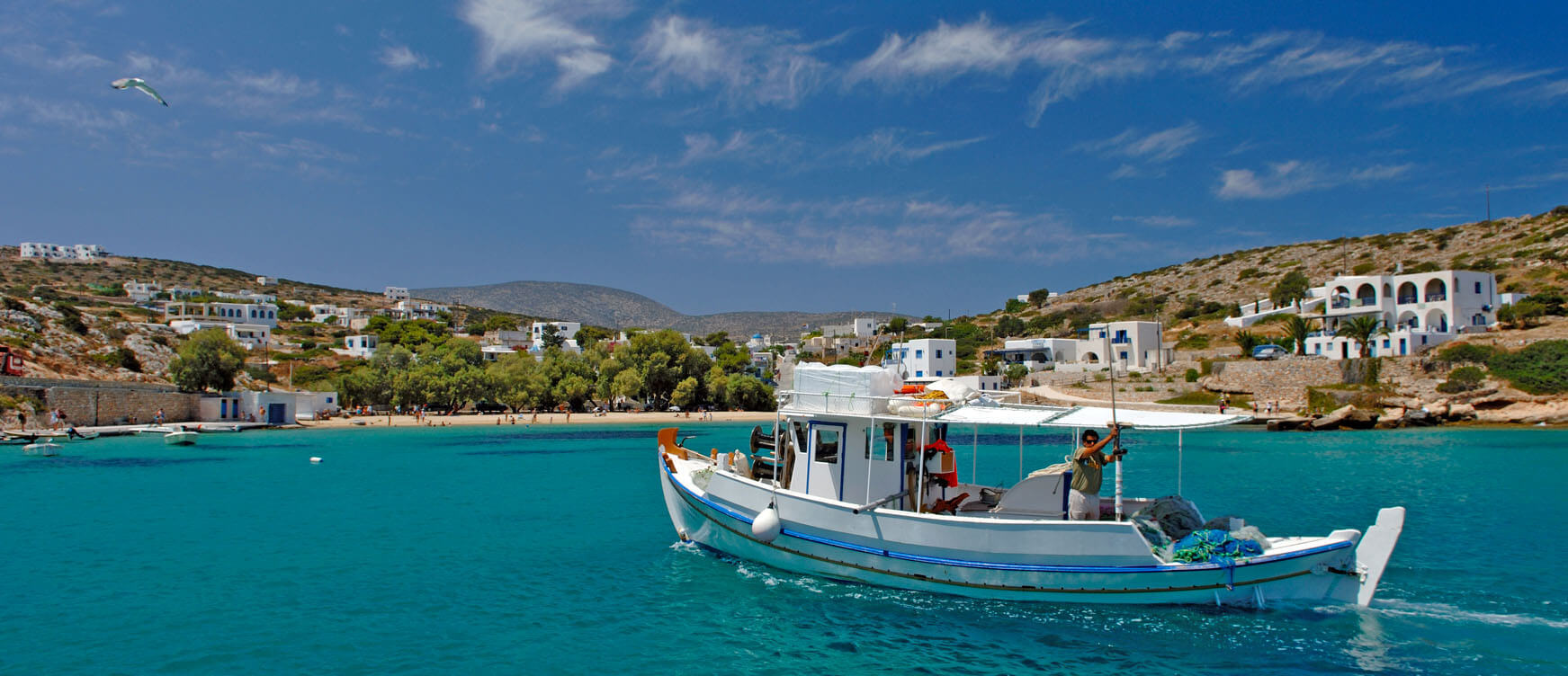Seaside village of the island with the beach and the whitewasahed houses in the background and a fishing boat in the blue sea