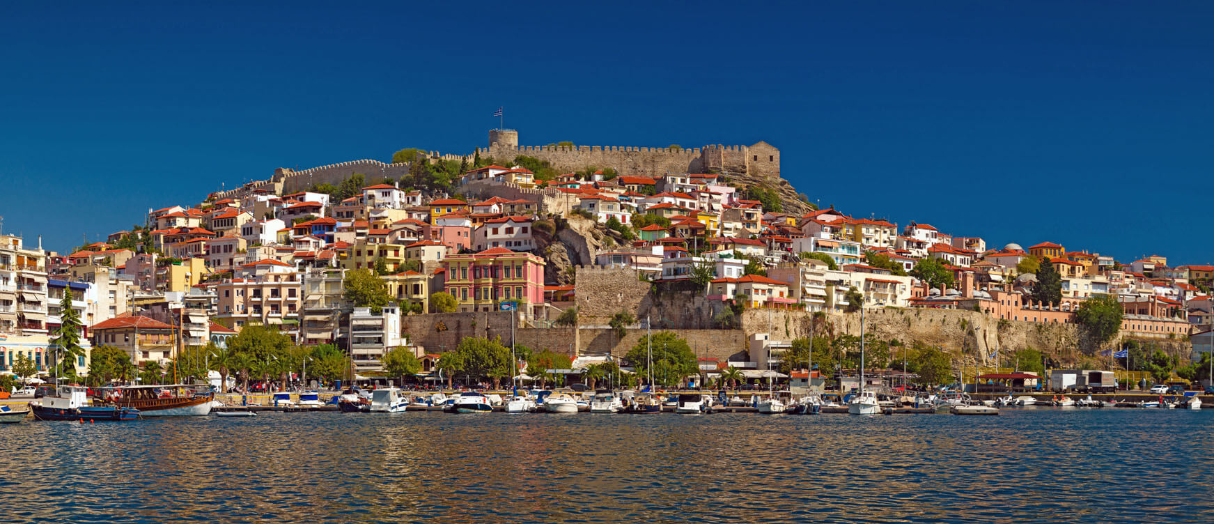 Panoramic view of the port of the city with many traditional houses and the castle at the top