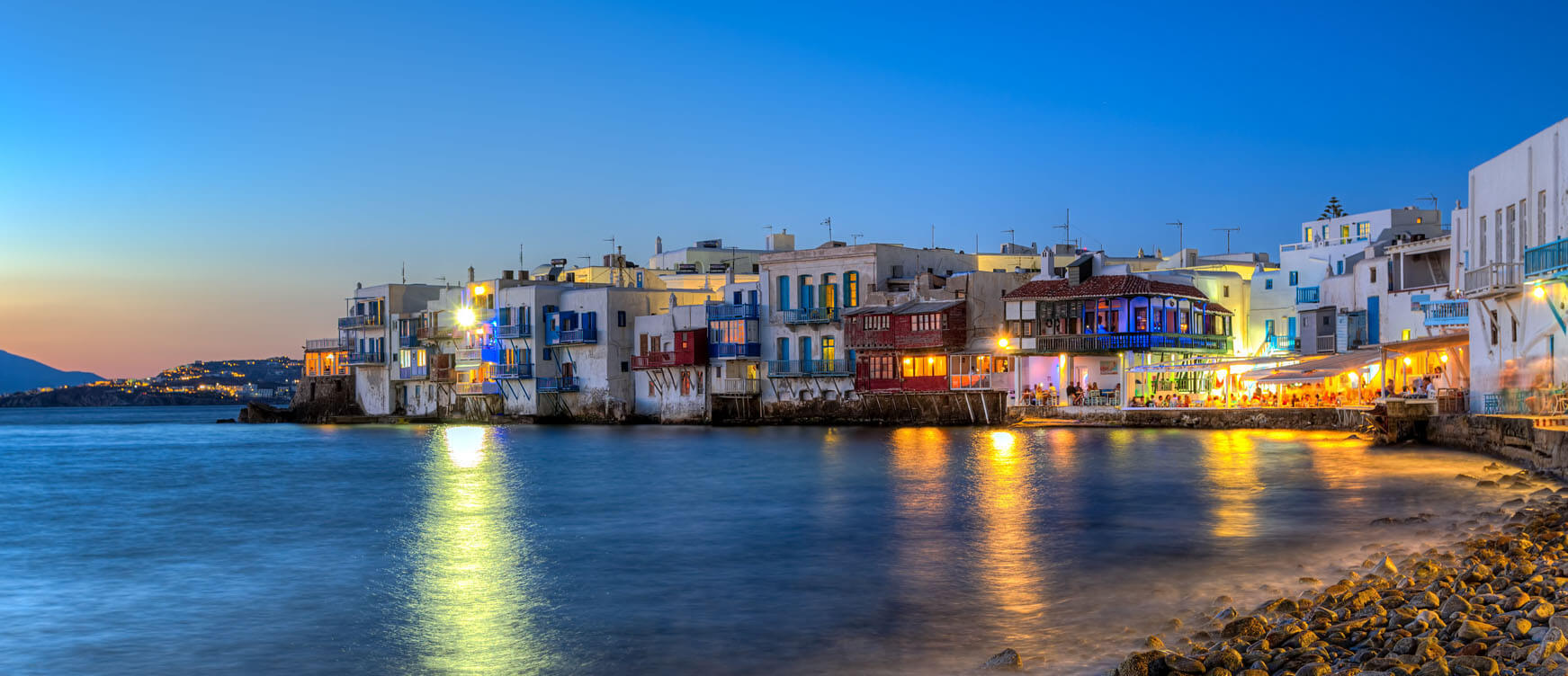 Small houses and restaurants on the sea at sunset.