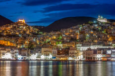 Νυχτερινή όψη μεγάλου οικισμού από τη θάλασσα με λόφους που στις κορυφές έχουν εκκλησίες.