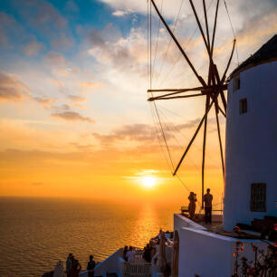 Windmill and a few people in front of the sunset. 