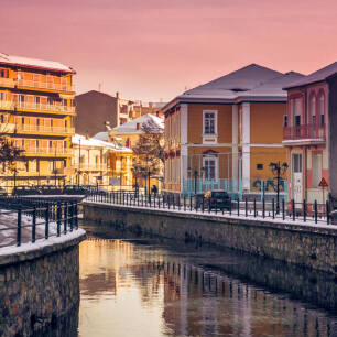 Winter shot of houses to the right and left of a river in Florina.