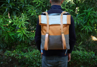 Άτομο που φορά ένα σακίδιο, που στέκεται μπροστά από το καταπράσινο φύλλωμα.