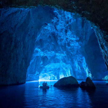 The inner part of a sea cave and a boat with visitors in the background