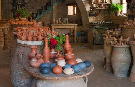 Interior with stone walls. Large clay jars on which there are many small clay objects. 