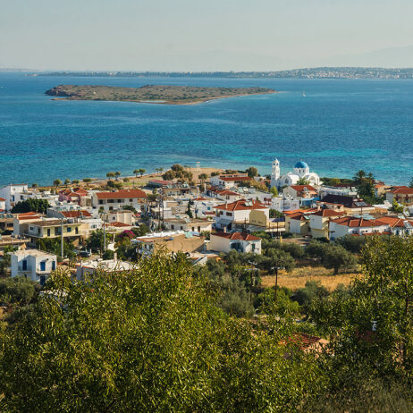 Seaside village with tiled rooftops, a white washed church with a blue dome and an islet in the background