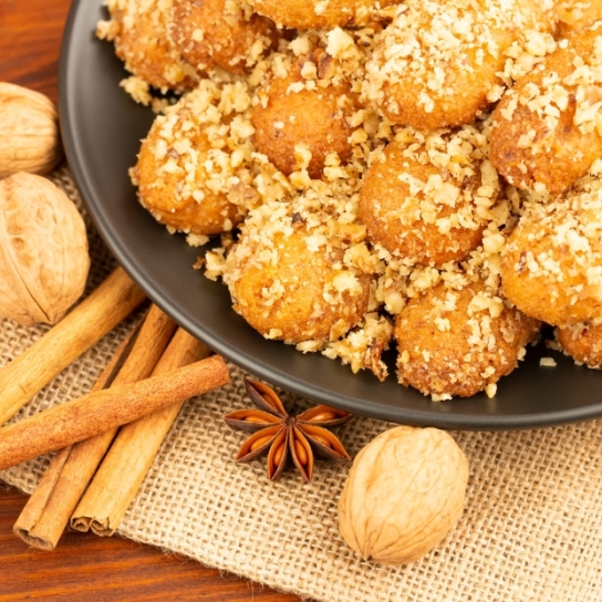 Greek biscuits known as melomakarona, dunked in honey syrup and sprinkled with crushed walnuts sprinkled and cinnamon spice