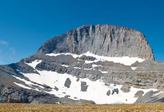Round and rocky mountain top with little snow and characteristic belts. 