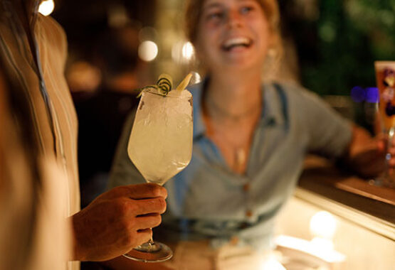 A woman laughs and has fun in the evening at an outdoor bar with drinks.
