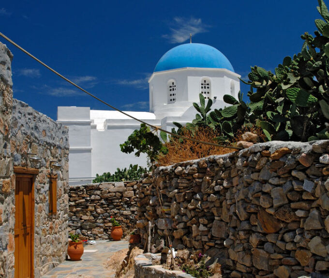 Άποψη πετρόκτιστού σπιτιού και στο βάθος φαίνεται η εκκλησία της Παναγίας με το γαλάζιο τρούλο