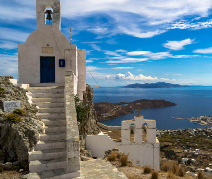 2 small white churches with bell tower and harbor view 