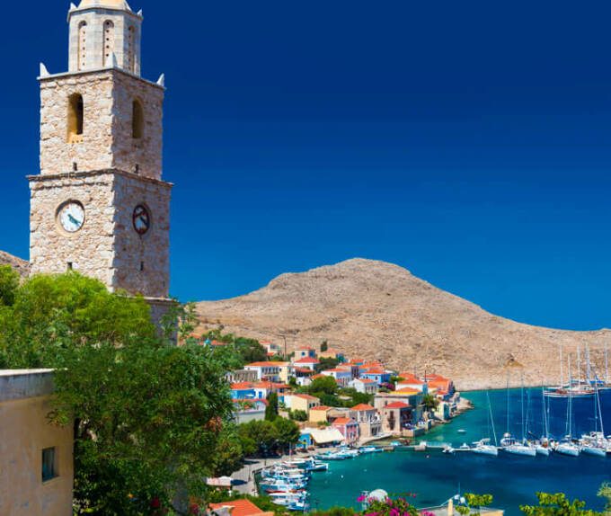 Church with bell tower overlooking the port of the island with the picturesque houses in the background