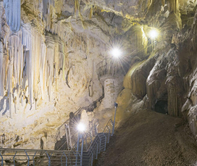 Εσωτερικό μεγάλου σπηλαίου με σταλακτίτες και ένα διάδρομο για τους επισκέπτες με φώτα.