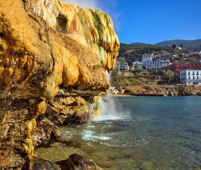 Άποψη των λουτρών της Αιδηψού, με απόκρημνα βράχια και με τη γαλάζια θάλασσα