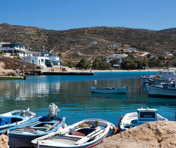 Λιμανάκι με μικρές βάρκες. Στο βάθος λίγα σπίτια και μια παραλία.