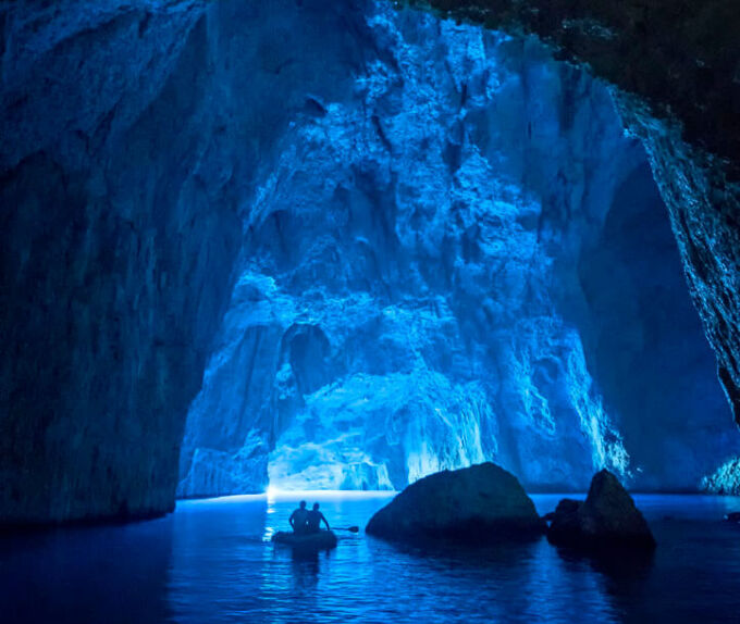 The inner part of a sea cave and a boat with visitors in the background