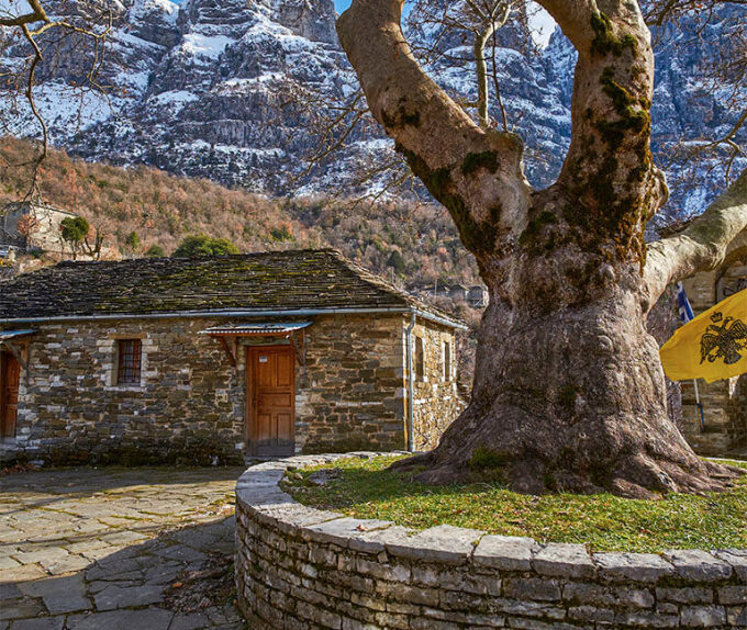 Χειμερινή άποψη στο Πάπιγκο ενός πετρόκτιστου σπιτιού κάτω από ένα ψηλό βουνό.