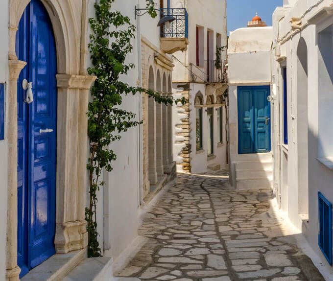 Stone alley in Panormos village, between the traditional houses with the blue doors