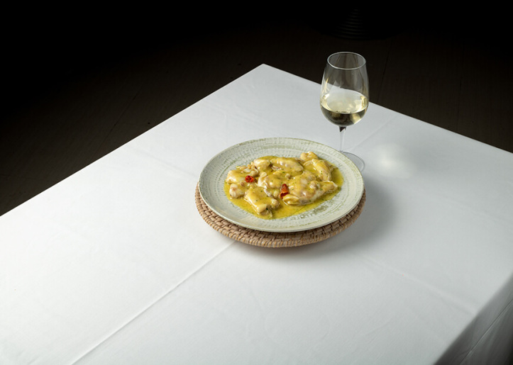 a table with a dish of food and a glass of wine