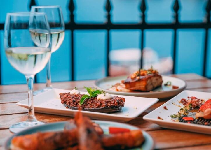 Served dishes on table along with two glasses of white wine