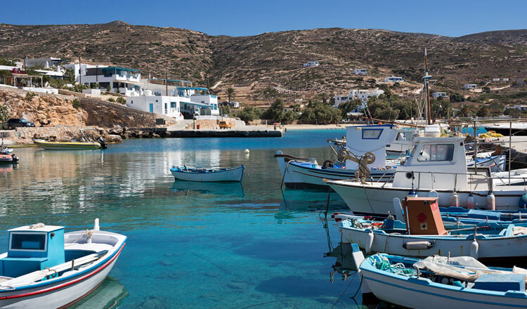 Λιμανάκι με μικρές βάρκες. Στο βάθος λίγα σπίτια και μια παραλία.