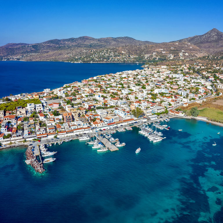 Γραφικό παραθαλάσσιο ηλιόλουστο χωριό με κεραμοσκεπές πάνω σε χερσόνησο.