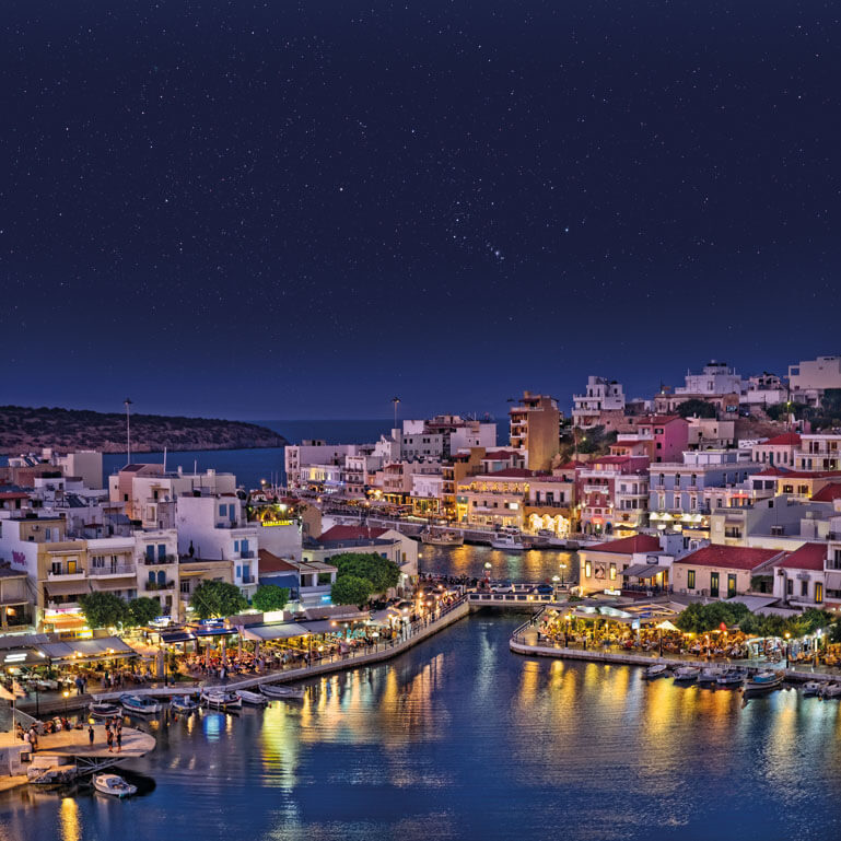 Πανοραμική άποψη της πόλης του Αγίου Νικολάου, με τα παραδοσιακά σπίτια και το φωταγωγημένο λιμάνι τη νύχτα