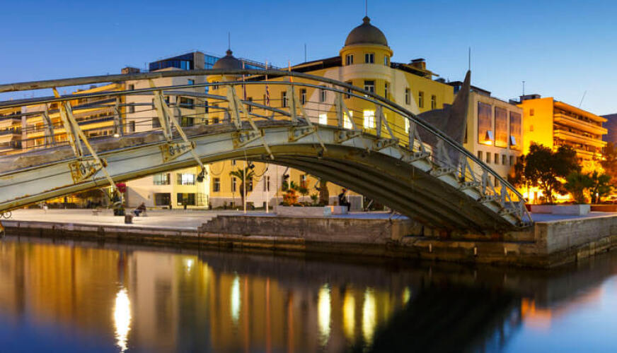 Waterfront and metal bridge at sunset with lights on. 