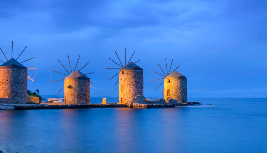 Four windmills made of stone on the sea at sunset. 