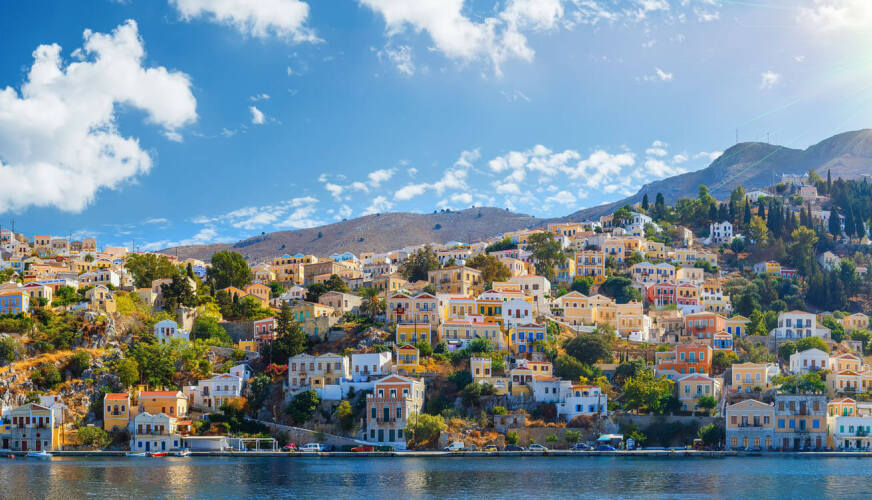 Παραθαλάσσιο παραδοσιακό χωριό με χρωματιστά σπίτια και δέντρα κόντρα στον ήλιο