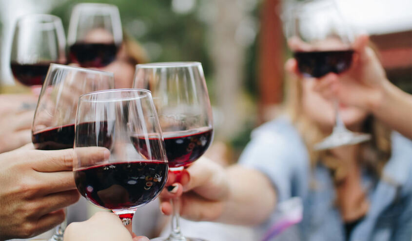 people tossing their clear wine glasses